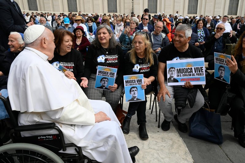 El papa Francisco saluda a un grupo de visitantes argentinos que sostienen imágenes del padre Carlos Mugica, sacerdote y activista argentino, tras la audiencia general del papa en el Vaticano el 8 de mayo de 2024. (CNS/Vatican Media)