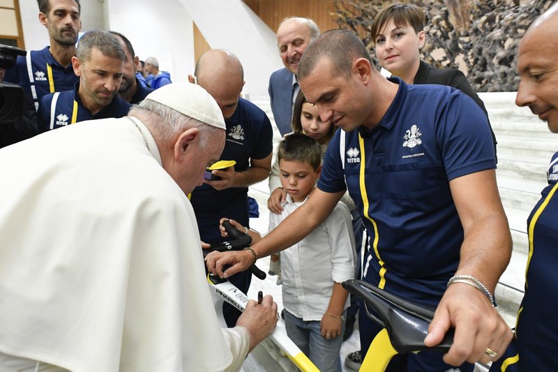 El Papa Francisco firma una bicicleta montada por Rien Schuurhuis, miembro de Athletica Vaticana, el equipo deportivo del Vaticano, después de su audiencia general semanal del 9 de agosto de 2023, en la sala de audiencias del Vaticano. La bicicleta fue montada en la carrera masculina de élite en carretera el 6 de agosto en los Campeonatos del Mundo de Ciclismo en Glasgow, Escocia, y será subastada para recaudar fondos para el Dispensario Santa Marta, una clínica pediátrica en el Vaticano. (CNS photo/Vatican Media)