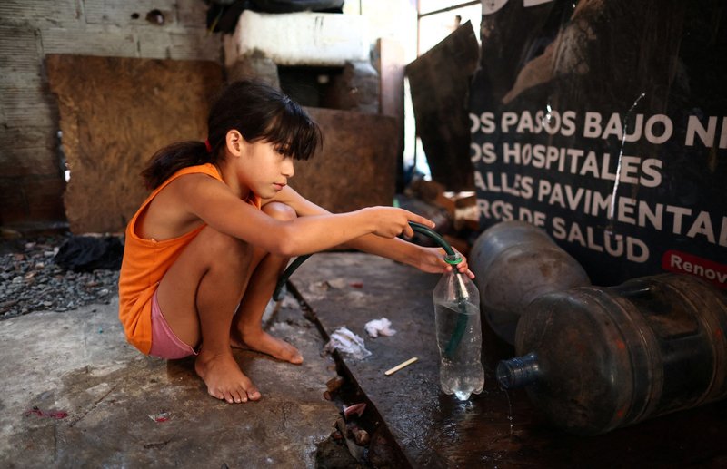 Una niña llena una botella con una manguera para llevar agua potable a su casa en un barrio pobre de Buenos Aires, Argentina, 27 de febrero de 2024. (Foto de OSV News/Agustin Marcarian, Reuters)