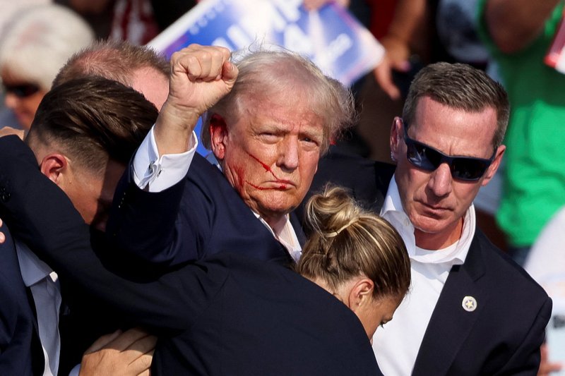El candidato presidencial republicano y expresidente de Estados Unidos Donald Trump gesticula, con la cara ensangrentada, es asistido por guardias después de que se produjeran disparos durante un mitin de campaña en el Butler Farm Show en Butler, Pensilvania, el 13 de julio de 2024. Un fiscal local dice que el presunto pistolero y al menos un asistente han muerto. (OSV News photo/Brendan McDermid, Reuters)