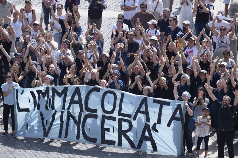 Detrás de una pancarta que dice en italiano: “La Inmaculada vencerá”, una cita de San Maximiliano Kolbe, un grupo de personas saludan y vitorean en la Plaza de San Pedro del Vaticano tras unirse al Papa Francisco en el rezo de la oración del Ángelus el 15 de agosto de 2024, festividad de la Asunción de María. (Foto CNS/Vatican Media)