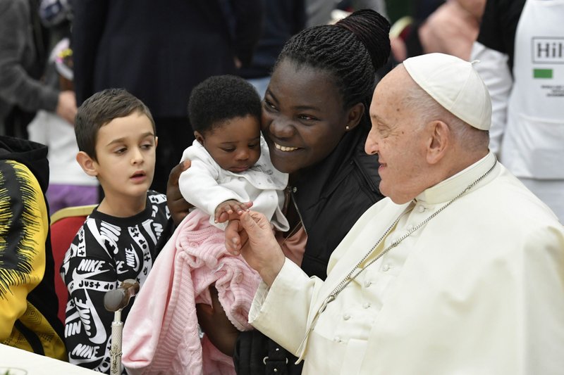 El Papa Francisco saluda a una mujer y a un niño durante un almuerzo en la sala de audiencias del Vaticano el 19 de noviembre de 2023, la Jornada Mundial de los Pobres. (Foto CNS/Vatican Media)