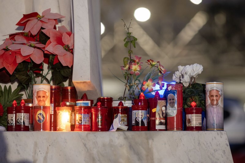 Velas votivas y flores se ven en la base de una estatua de San Juan Pablo II fuera del hospital Gemelli de Roma el 19 de febrero de 2025, donde el Papa Francisco está siendo tratado por una neumonía doble. (Foto CNS/Pablo Esparza)
