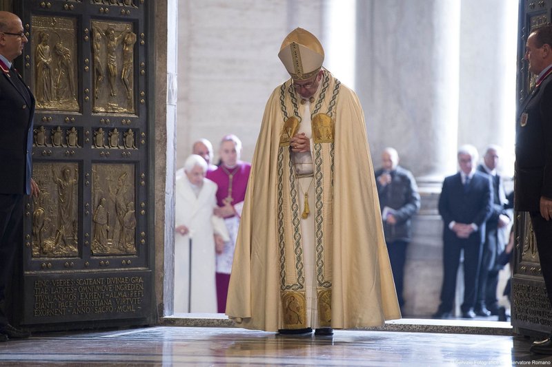 El Papa Francisco reza tras atravesar la Puerta Santa para inaugurar el Año Jubilar de la Misericordia en la Basílica de San Pedro del Vaticano, en esta foto de archivo del 8 de diciembre de 2015. Al fondo, a la izquierda, el papa emérito Benedicto XVI, que entró por la Puerta Santa después del papa Francisco. El Papa ha aprobado el lema «Peregrinos de esperanza» para el Año Santo 2025. (CNS photo/Vatican Media)