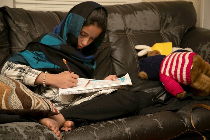 Una joven trabaja en sus tareas en su casa en Bowling Green, Kentucky, el 27 de noviembre de 2021. La familia Zadran, refugiados afganos que huyen de los talibanes, llegó a Bowling Green tras pasar una temporada en una base militar de Nuevo México. La Conferencia de Obispos Católicos de Estados Unidos dijo que no renovará sus acuerdos de cooperación con el gobierno federal relacionados con los servicios para niños y el apoyo a los refugiados después de que sus asociaciones de larga data con el gobierno federal en esas áreas se volvieran “insostenibles”. (Foto OSV News/Amira Karaoud, Reuters)