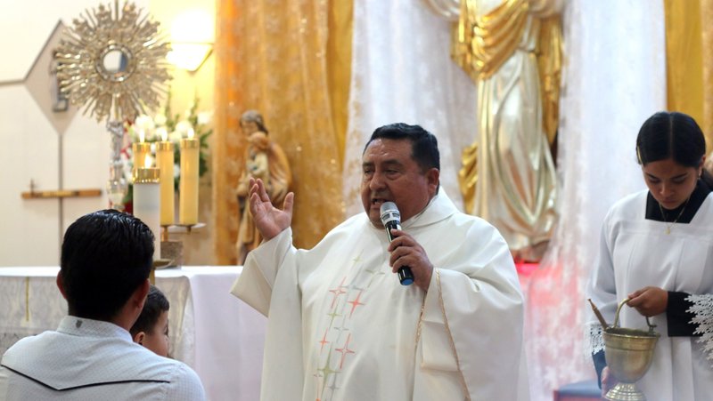 El padre Walter Paredes bendice a una familia al final de la Misa vespertina en la iglesia Mary Immaculate en Pacoima, el jueves 23 de mayo. (Pablo Kay)