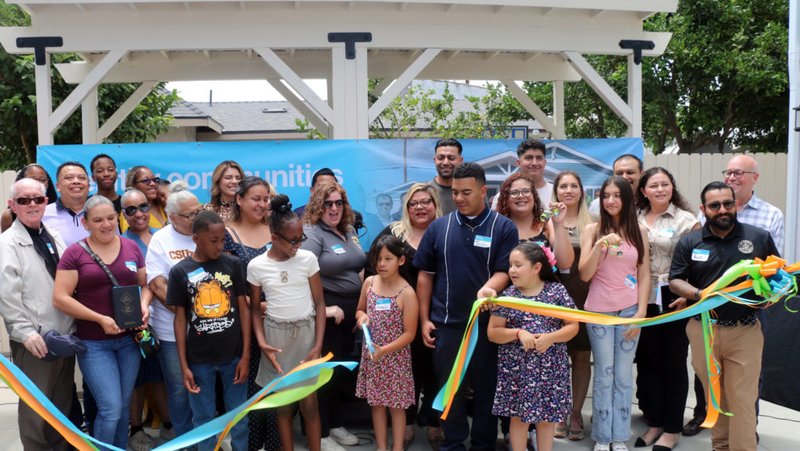 Las familias beneficiarias de nuevas casas de Habitat for Humanity cortan la cinta durante un acto de bendición el 12 de julio, con la participación del obispo auxiliar de Los Ángeles, Matthew Elshoff. (Giacomo Ammazzalorso)
