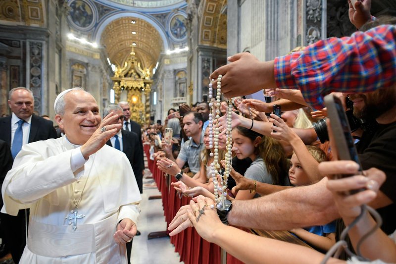 El Papa León XIV bendice rosarios y saluda a los peregrinos dentro de la Basílica de San Pedro en el Vaticano el 20 de agosto de 2025, tras su audiencia general semanal. El Papa los visitó al término de la audiencia para ofrecerles su bendición, ya que la sala Pablo VI había alcanzado su aforo máximo. (Foto CNS/Vatican Media)