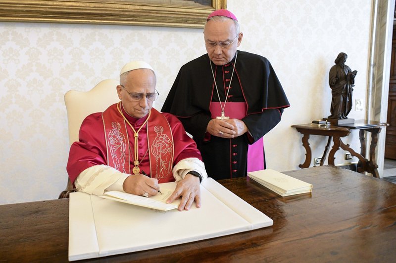 El Papa León XIV firma su primera exhortación apostólica, “Dilexi Te” (“Te he amado”), en la biblioteca del Palacio Apostólico del Vaticano el 4 de octubre de 2025, festividad de San Francisco de Asís, en presencia del arzobispo Edgar Peña Parra, secretario sustituto para los asuntos generales de la Secretaría de Estado del Vaticano. La exhortación se publicará el 9 de octubre. (Foto CNS/Vatican Media)