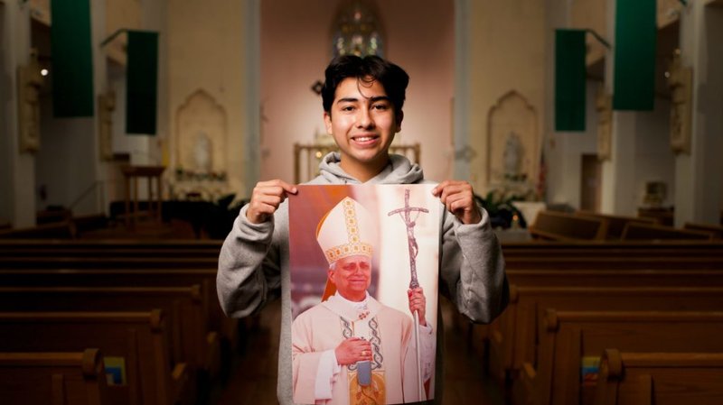 Ezequiel Ponce, de 17 años, con un retrato del Papa León XIV dentro de la iglesia Our Lady of Perpetual Help en Downey. (Reese Cuevas)
