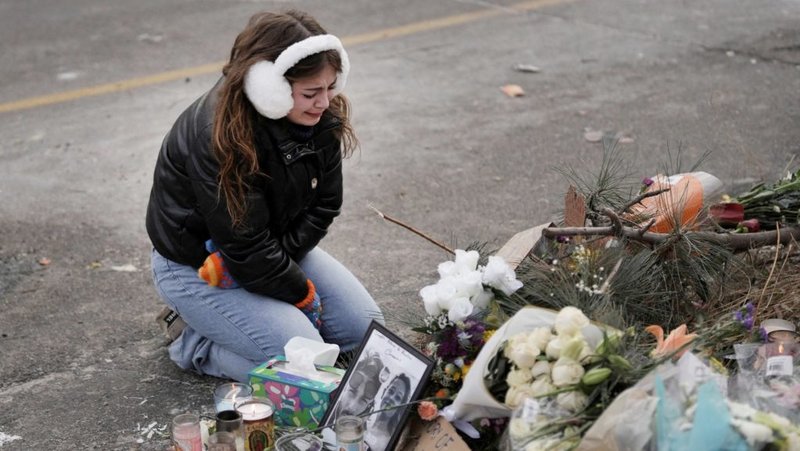 Una joven visita un memorial improvisado en Minneapolis el 25 de enero, en el lugar donde un hombre fue asesinado a tiros por agentes federales que intentaban detenerlo el 24 de enero. El arzobispo Bernard A. Hebda, de St. Paul y Minneapolis, junto con otros líderes de la Iglesia, ha hecho un llamamiento a la paz en medio de las crecientes tensiones. (OSV News/Tim Evans, Reuters)