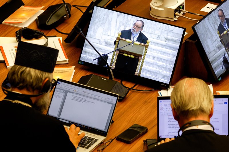 Los participantes en el Sínodo toman notas en sus ordenadores mientras el padre Carlos María Galli, teólogo argentino, habla en un monitor de vídeo durante una sesión de trabajo de la asamblea del Sínodo de los Obispos en la Sala de Audiencias Pablo VI del Vaticano, el 13 de octubre de 2023. Los informes finales de dos grupos de estudio del Sínodo sobre la sinodalidad, sobre la formación para el sacerdocio y sobre la presencia de la Iglesia en los espacios digitales, se publicaron el 3 de marzo de 2026. (Foto CNS/Lola Gómez)
