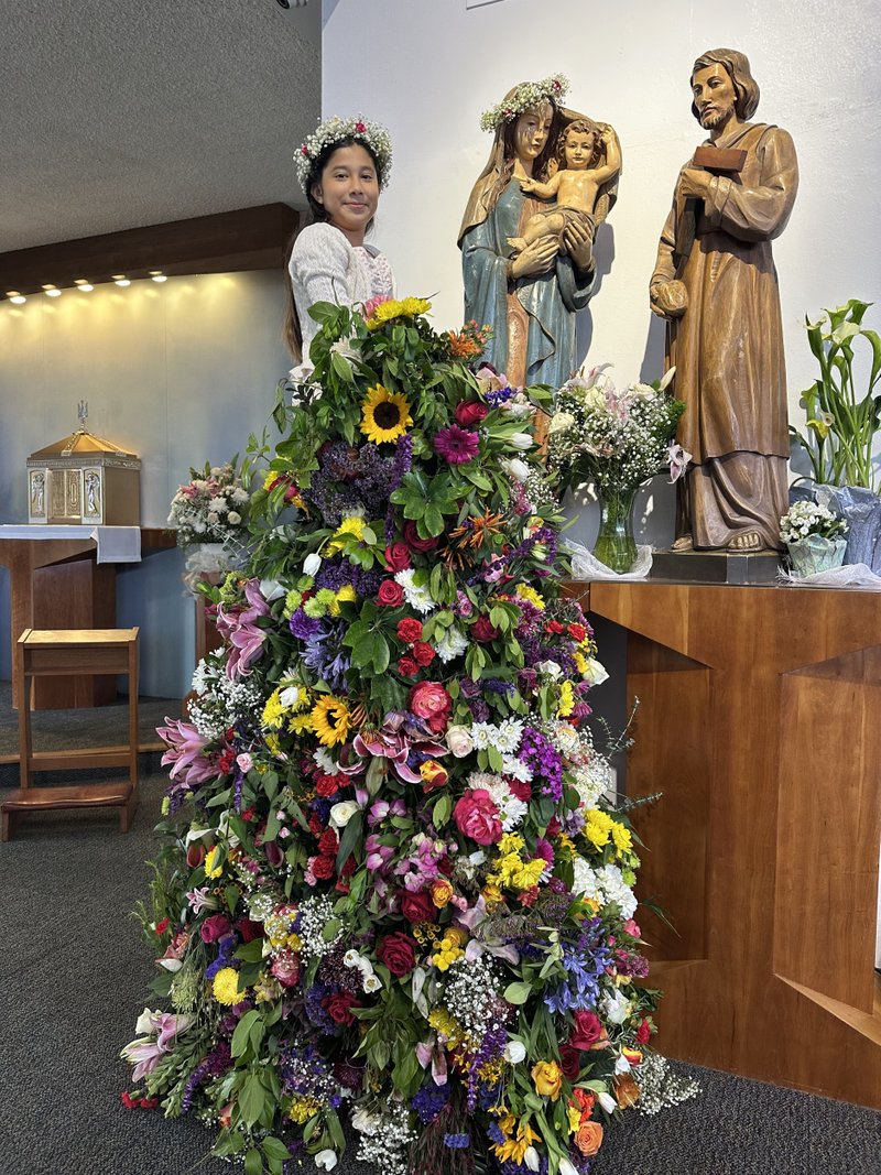 Amani Diaz, a student at St. Raphael School in Santa Barbara, crowns a statue of the Virgin Mary during a May crowning event. (St. Raphael School)