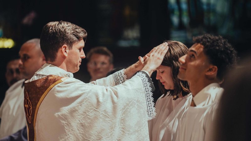 El padre Matthew Wheeler, párroco de Our Savior en la USC, bendice a quienes se incorporan a la Iglesia católica durante la misa de la Vigilia Pascual del 4 de abril. (Centro Católico Caruso de la USC)