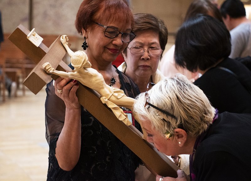Vicky Samia holds a crucifix as faithful take turns venerating it on Good Friday. VICTOR ALEMÁN/ANGELUS NEWS