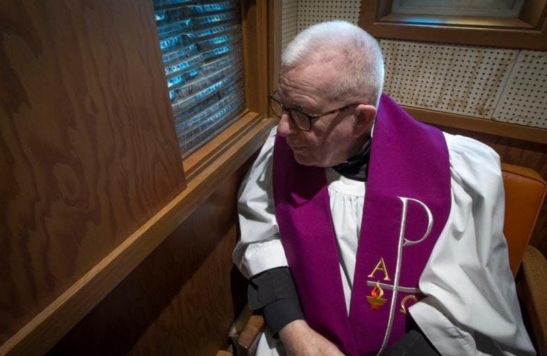 Father Lawrence C. Goode sits in his confessional May 8