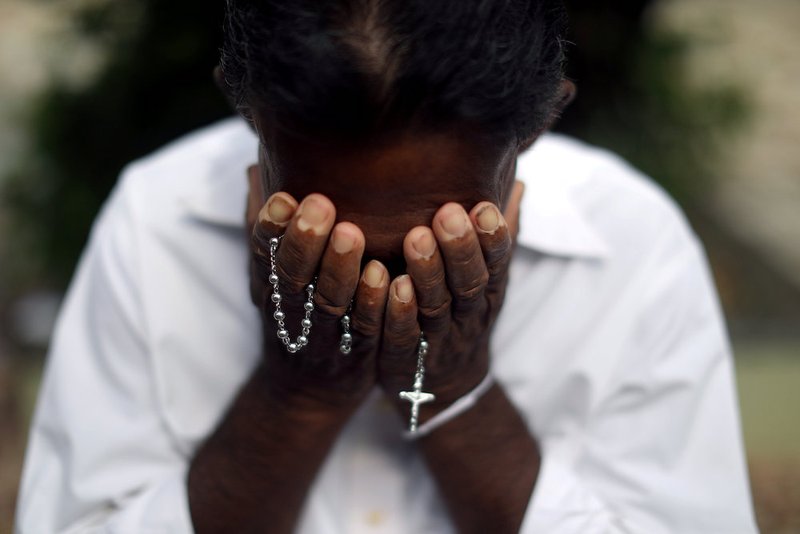 A person mourns near a victim's grave at Sellakanda Catholic cemetery in Negombo