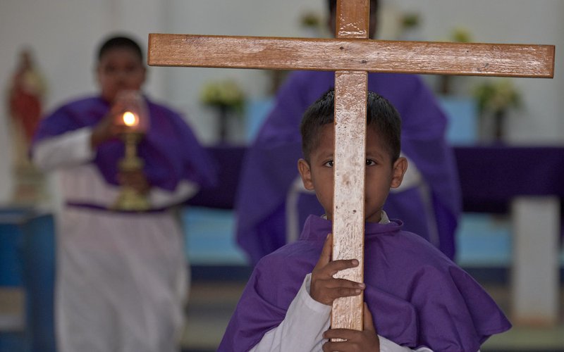 A boy carries the cross out of the sanctuary at the end of Catholic Mass in Lethem