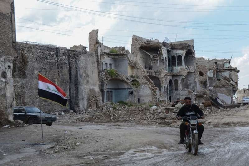 A man rides a motorcycle in the old city of Mosul