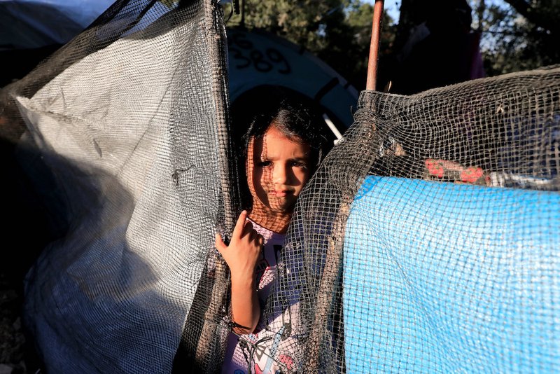 A girl looks out from a makeshift tent Sept. 17 at a camp for refugees and migrants on the island of Lesbos