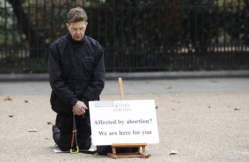 An activist prays outside an abortion clinic in London March 14