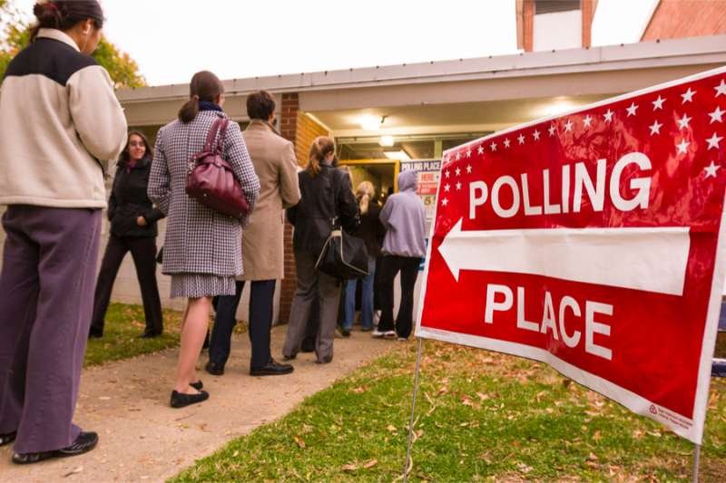 Voting polling place sign and people lined up on electon day. Credit: Rob Crandall / Shutterstock