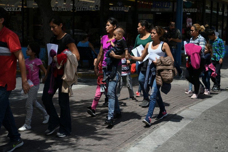 Migrant families seeking asylum walk from a bus depot to a Catholic Charities humanitarian respite center just after being released from federal detention in McAllen