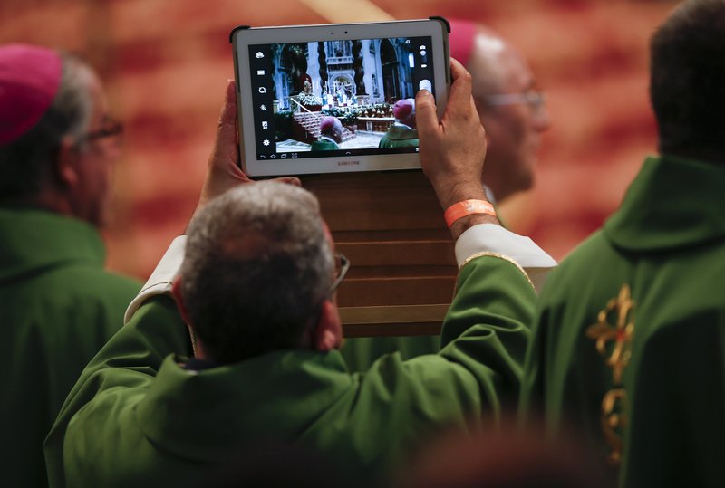 A priest take pictures with a tablet as Pope Francis celebrates Mass in St. Peter's Basilica at the Vatican in this July 7