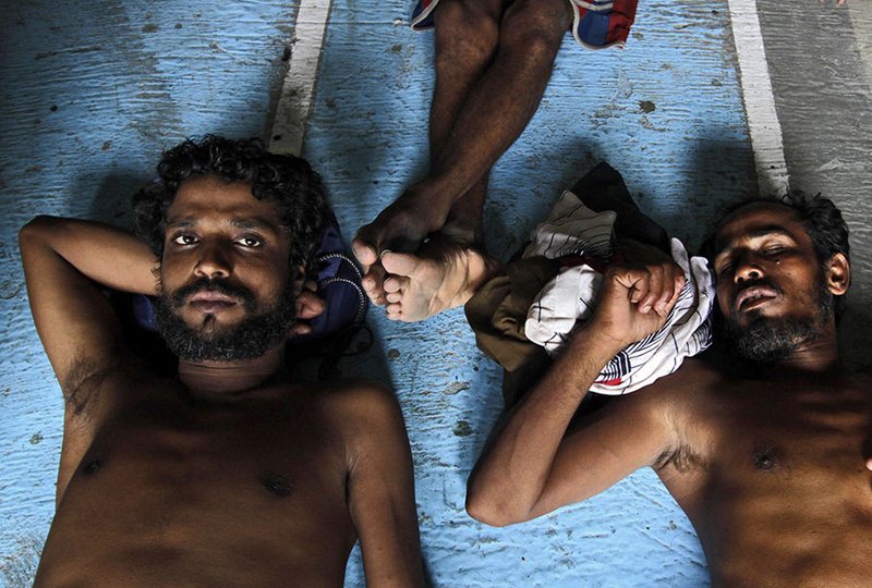 Rohingya and Bangladeshi men lie on the floor inside a refugee camp at Kuala Langsa