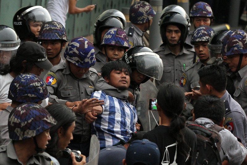 Police officers detain a student taking part in a rally demanding peace May 12 at the war-torn section of Yangon