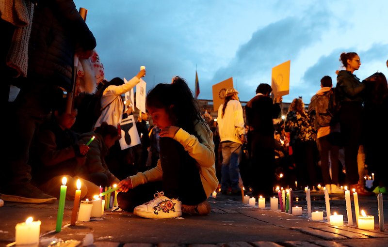 A girl lights a candle during a protest in early July against the killing of social leaders in Bogota
