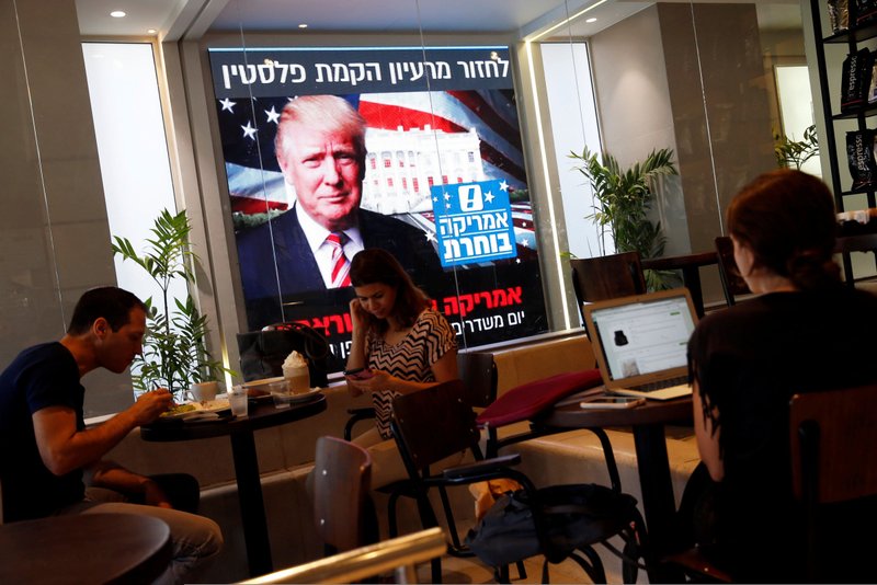 People dine at a Tel Aviv coffee shop Nov. 9 as an image of President-elect Donald Trump is displayed on a monitor. (CNS photo/Baz Ratner