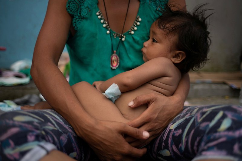 A woman from Honduras holds her one-year-old daughter as they rest Oct. 23 in Huixtla