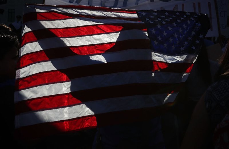 A pro-immigration activist holds a U.S. flag in front of the U.S. Supreme Court in Washington