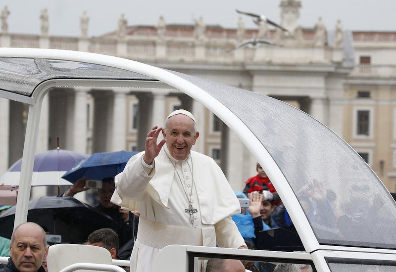 Pope Francis waves as he leaves his general audience in a rainy St. Peter's Square at the Vatican April 10