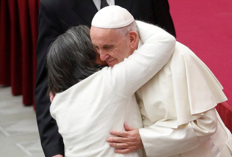 A woman embraces Pope Francis as he arrives to lead his general audience in Paul VI Hall Dec. 12 at the Vatican. (CNS photo/Max Rossi
