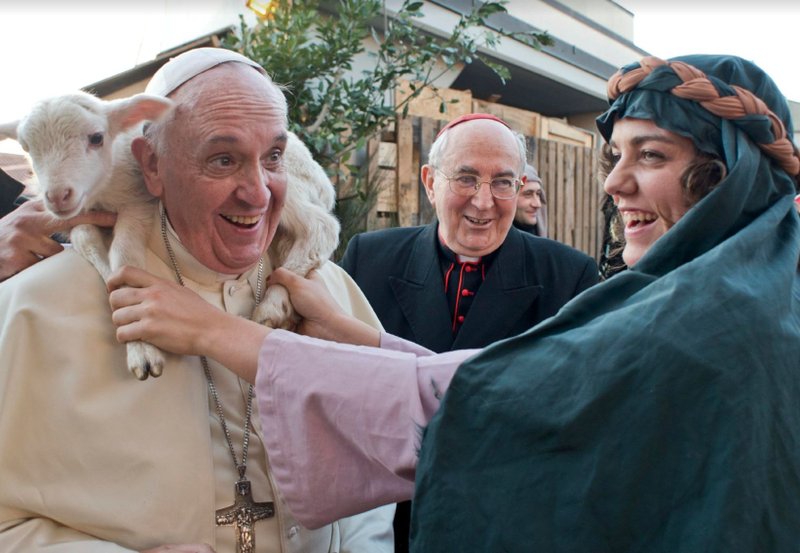 A woman dressed as a character from a Nativity scene puts a lamb around the neck of Pope Francis as he arrives to visit the Church of St. Alfonso Maria dei Liguori in Rome. (CNS file photo/L'Osservatore Romano via Reuters)