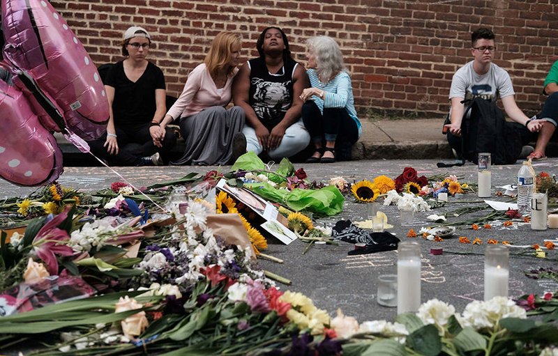 People sit by a memorial of flowers in Charlottesville