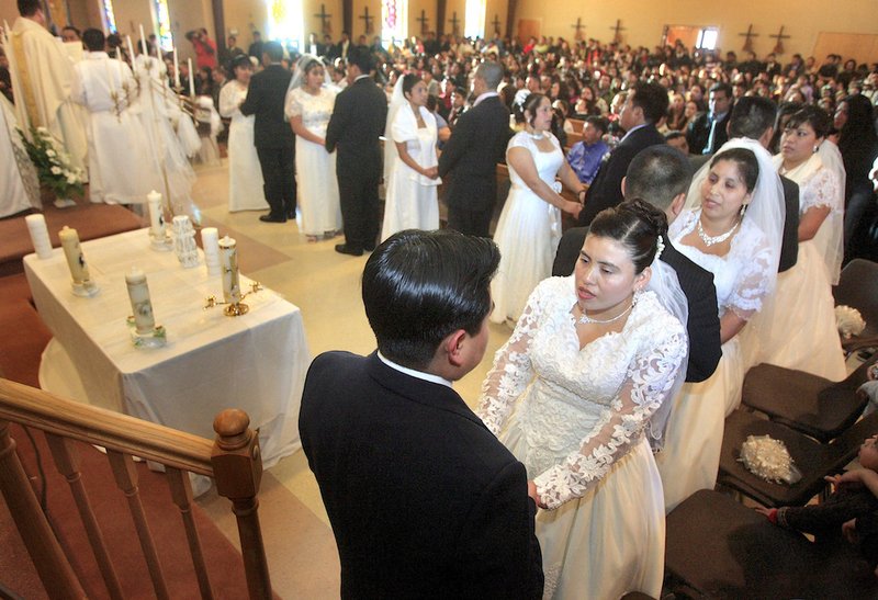 Couples exchange vows during a wedding service at St. Michael the Archangel Church in Georgetown