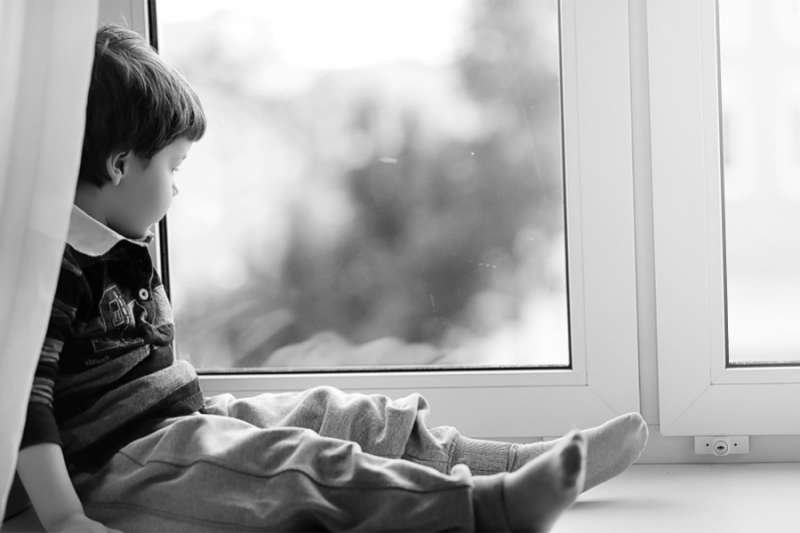 Child looks out of the window. Credit: alexkich_Shutterstock