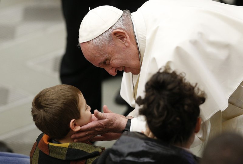 Pope Francis greets a boy as he meets the sick and disabled during his general audience in Paul VI hall at the Vatican Feb. 20