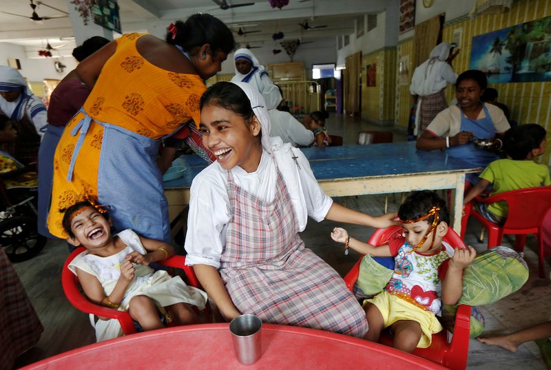 A member of the Missionaries of Charity laughs as she interacts with children in 2016 at Nirmala Shishu Bhavan