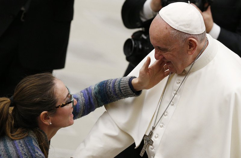 A woman touches Pope Francis' face during his general audience in Paul VI hall at the Vatican Jan. 16. (CNS photo/Paul Haring)