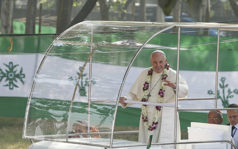 Pope Francis wears a garland as he greets the crowd before celebrating Mass and the ordination of priests in Suhrawardy Udyan park in Dhaka