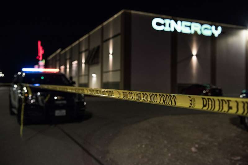 Police cars and tape block off a crime scene outside the Cinergy Odessa movie theater where a gunman was shot and killed on August 31