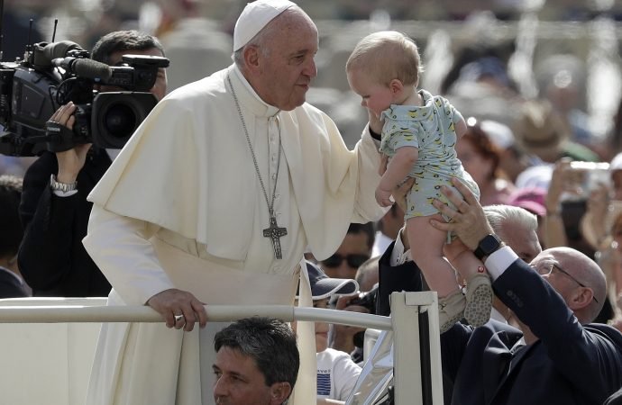 Pope Francis blesses a baby as he arrives for his weekly general audience in St. Peter's Square