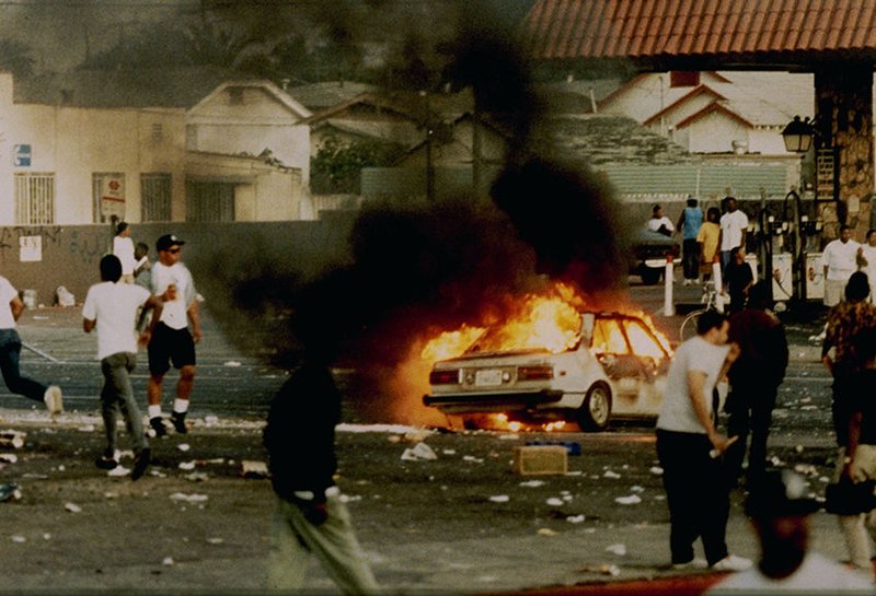 A car burns as looters take to the streets at the intersection of Florence and Normandie Avenues