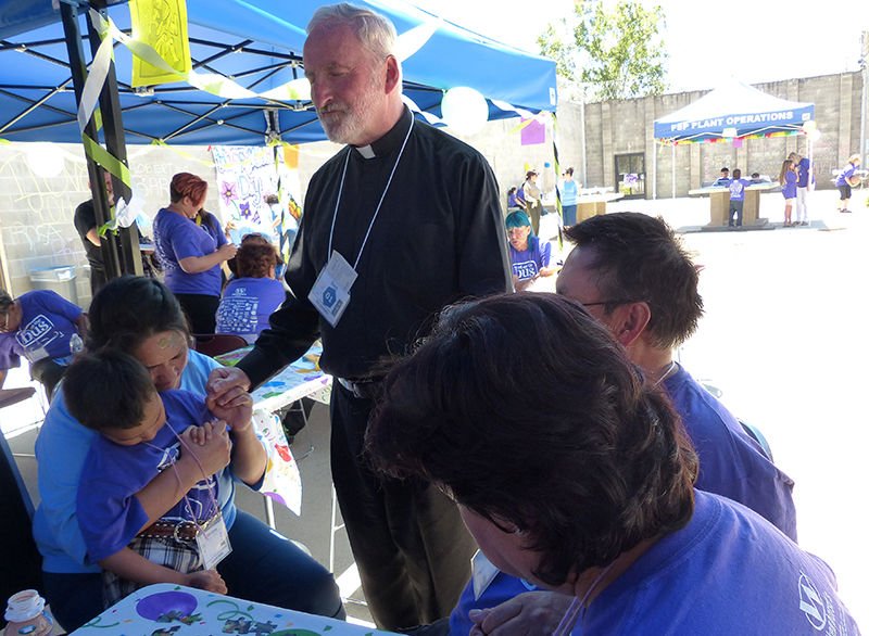 Bishop David O’Connell prays with a family at Folsom State Prison on June 25. (photo/R.W. Dellinger)