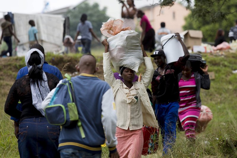 Zimbabwe nationals carry their bags before boarding a bus home from a camp for those affected by anti-immigrant violence near Durban