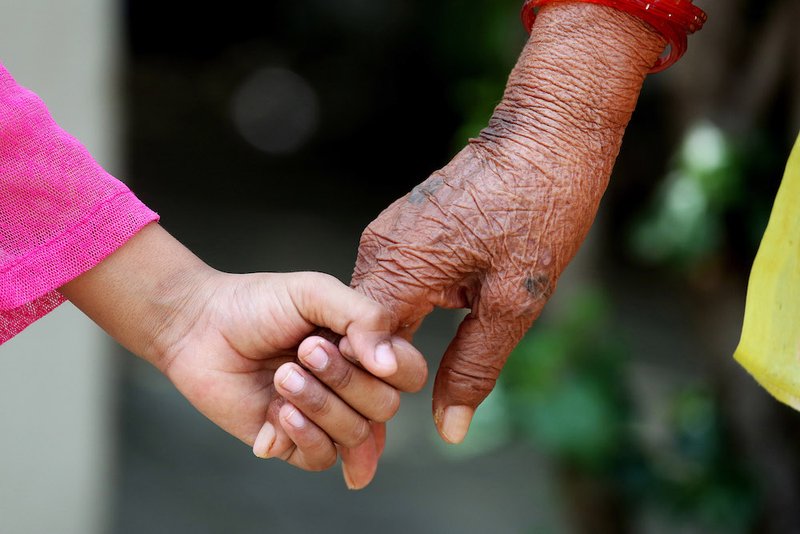 A girl holds the hand of an elderly person in Bhopal